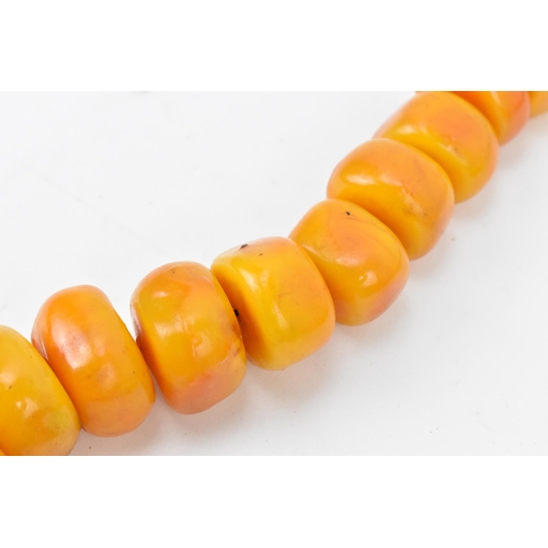 192 - A large Moroccan pressed amber bead necklace, with graduated block beads on string, wool fastening, ... 