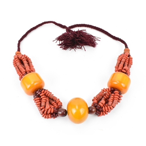 193 - A Moroccan Berber style pressed amber and coral bead necklace, with braided wool fastening, central ... 