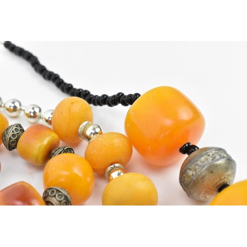 195 - A small group of Moroccan Berber style pressed amber and white metal necklaces