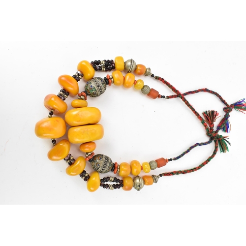 196 - Two Moroccan Berber style pressed amber and white metal, necklaces, one with coral, and enamel to th... 