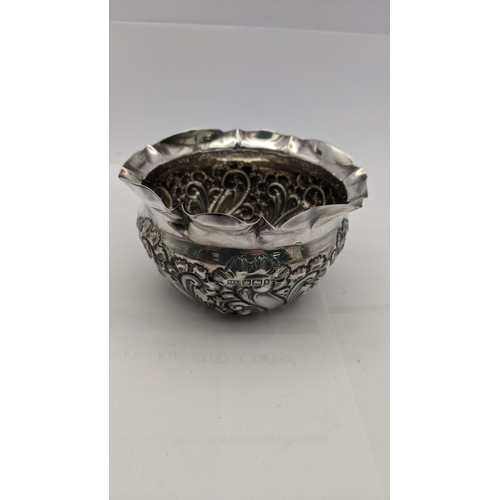 180 - A silver embossed floral pot having crimped shaped edges, 69.3g, together with a silver embossed thr... 