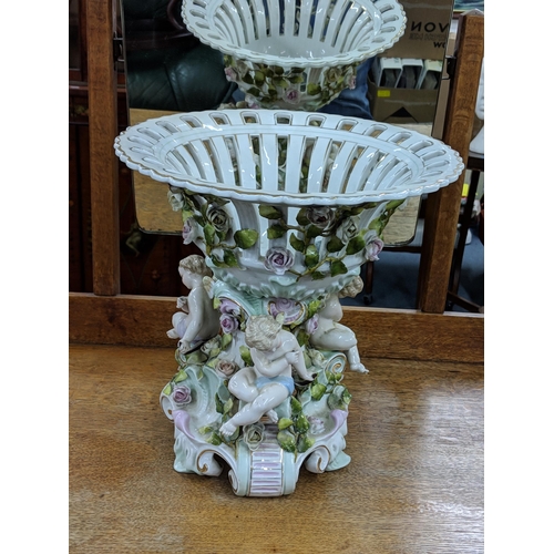 322 - A 20th century continental centrepiece with a pierced basket decorate with trailing flowers and thre... 