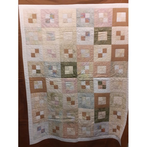 124 - A 20th Century handmade quilt in browns, cream, white, pinks, greens and blues having a geometric sq... 