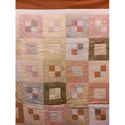 124 - A 20th Century handmade quilt in browns, cream, white, pinks, greens and blues having a geometric sq... 