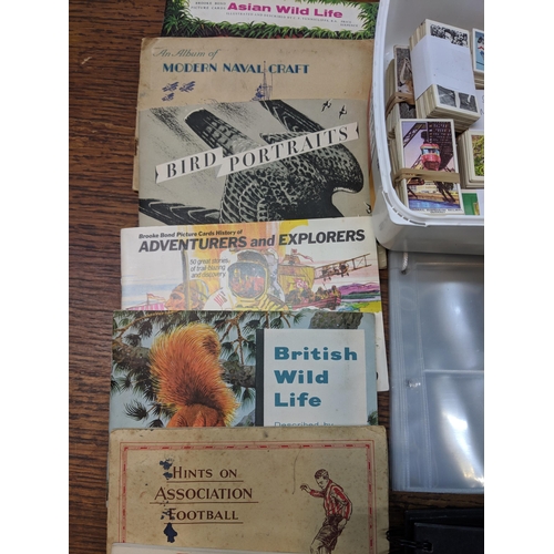 388 - Cigarette cards and tea card books and loose cards and in plastic wallets with French game cards Loc... 