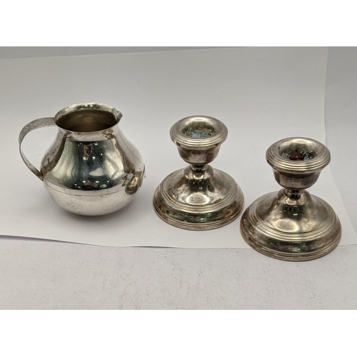 451 - A pair of silver candlestick holders hallmarked Birmingham 1978 together with a white metal milk jug... 