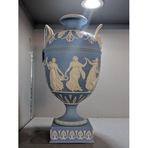 496 - A blue and white Wedgwood jasperware twin handled urn vase decorated with maidens, raised on a squar... 