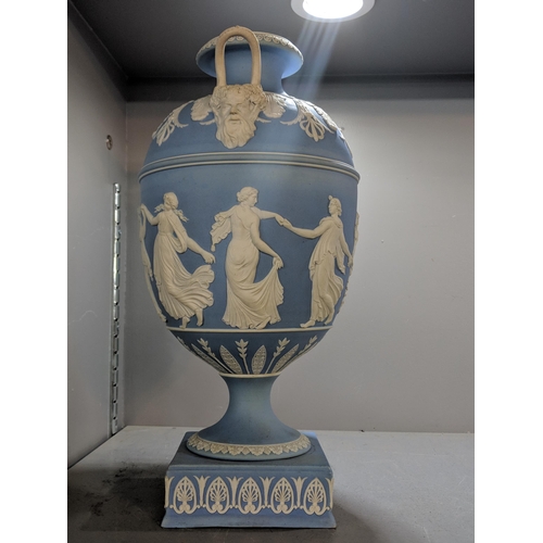 496 - A blue and white Wedgwood jasperware twin handled urn vase decorated with maidens, raised on a squar... 