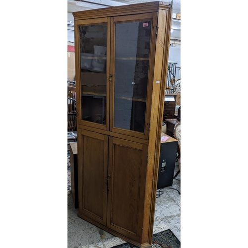 423 - A 19th century pine corner cabinet, twin glazed doors, with shaped internal shelves, over twin field... 