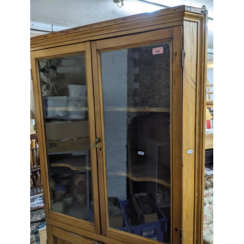 423 - A 19th century pine corner cabinet, twin glazed doors, with shaped internal shelves, over twin field... 