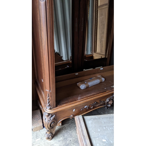 448 - A late 19th century walnut armoire having a carved floral and scroll frame, two mirrored doors, fitt... 