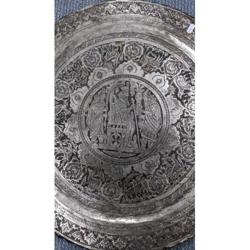 472 - An early 20th century Middle Eastern silver coloured charger decorated with a scene of figures to th... 