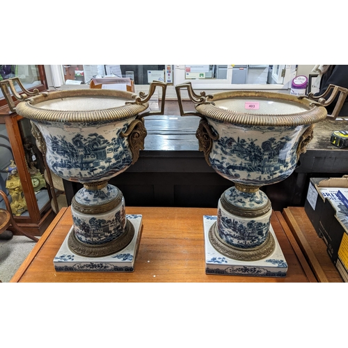 403 - A pair of modern Chinese style pedestal vases with brass mounts decorated with landscapes in blue an... 