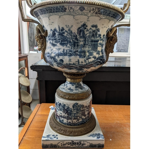 403 - A pair of modern Chinese style pedestal vases with brass mounts decorated with landscapes in blue an... 