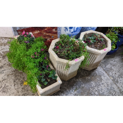 404 - A pair of octagonal garden composite stone planters with vertical fluted design on shaped plinth bas... 