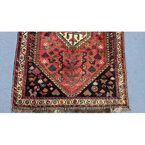 3 - A Persian Shiraz rug having a central motif, lozenge-shape field, tree motifs with small animals and... 