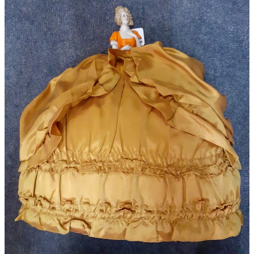 257 - A silk crinoline doll tea cosy having a porcelain body and gold coloured skirt, 39cm High together w... 