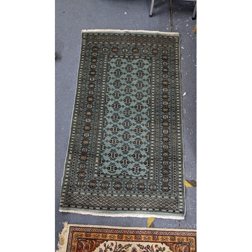 534 - Two hand woven rugs to include a Pakistani green ground rug with multi-guard borders and tasselled e... 