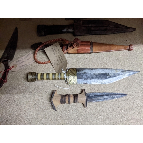 439 - A group of African daggers and a machete, some in leather sheaths, circa 1940 and a group of Nigeria... 