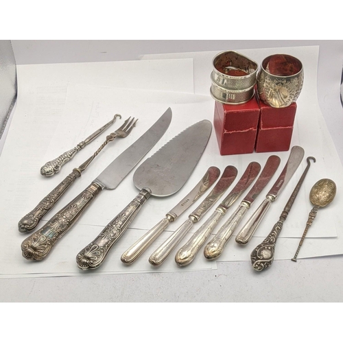 211 - Three silver napkin rings 55g silver handled knives, bread knife, button hook and cake knife
Locatio... 