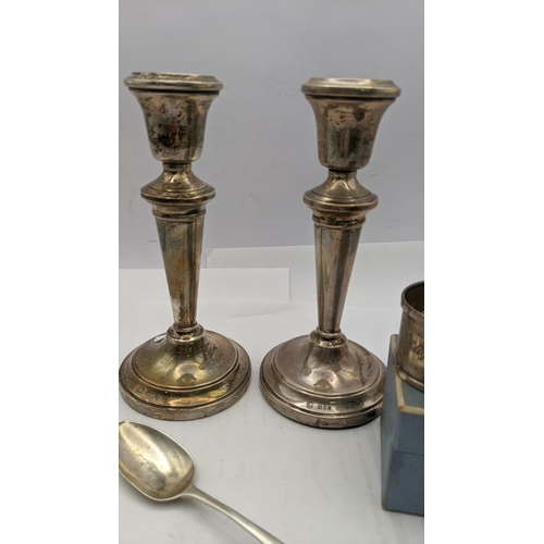 216 - Mixed silver to include a pair of weighted candle sticks a silver napkin ring and tea spoon 
Locatio... 