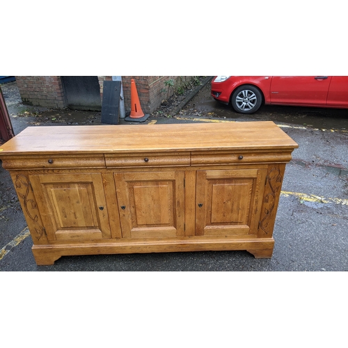 202 - A modern French style oak sideboard with three drawers and three doors, on bracket feet, 198cm long,... 