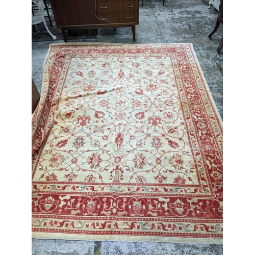 175 - A contemporary hand woven Afghan Zeigler rug, all over floral design in red and blue, on a sandy gro... 