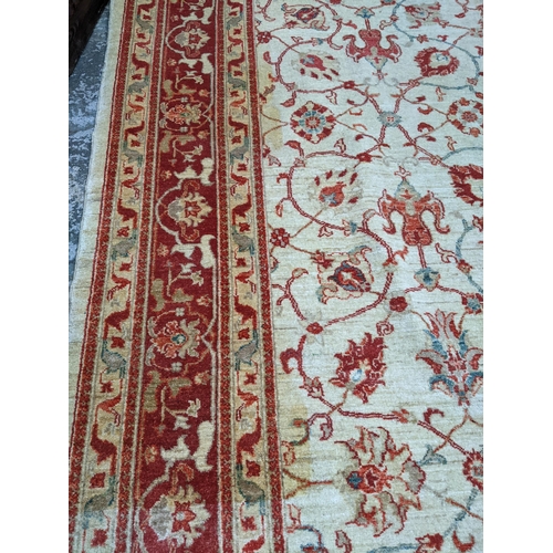 175 - A contemporary hand woven Afghan Zeigler rug, all over floral design in red and blue, on a sandy gro... 