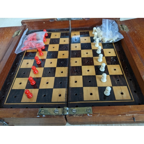 192 - A Victorian mahogany travelling chess set, the folding board with red and white plastic chess pieces... 