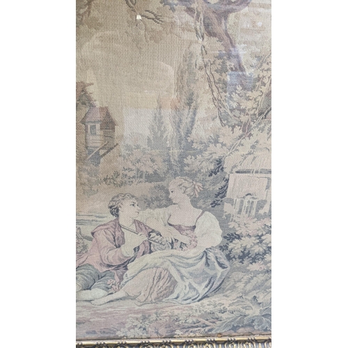 216 - A framed and glazed tapestry depicting a country scene, a man playing his flute, children with a goa... 