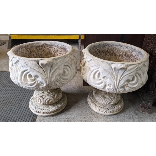 372 - A pair of reconstituted stoneware garden planters having moulded floral decoration and raised on cir... 