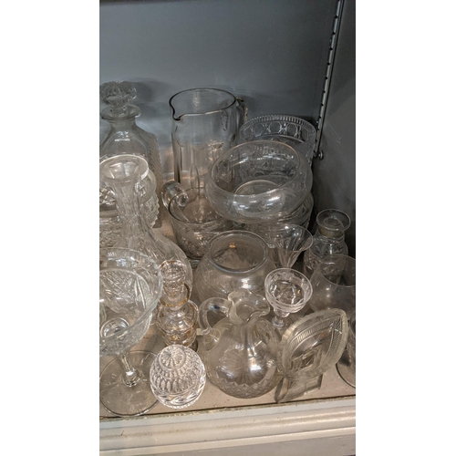 68 - A mixed lot of glassware to include a smoked glass jug, crystal cut decanters, a pair of cube style ... 