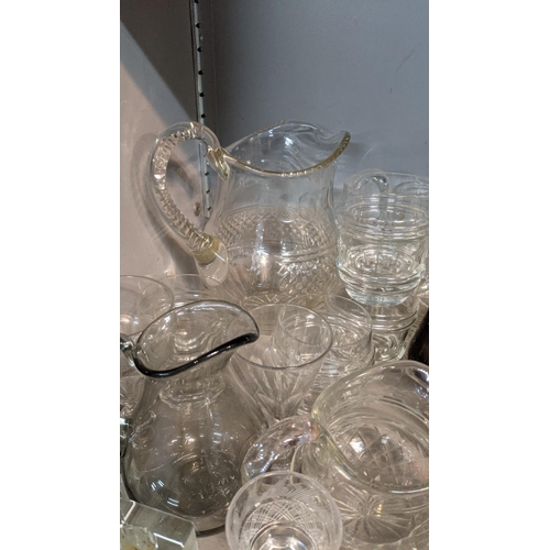 68 - A mixed lot of glassware to include a smoked glass jug, crystal cut decanters, a pair of cube style ... 