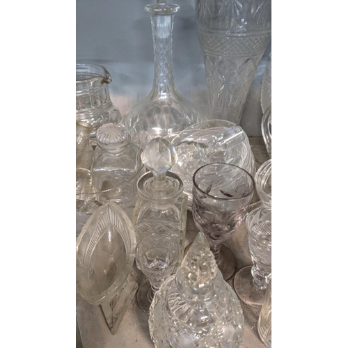 68 - A mixed lot of glassware to include a smoked glass jug, crystal cut decanters, a pair of cube style ... 