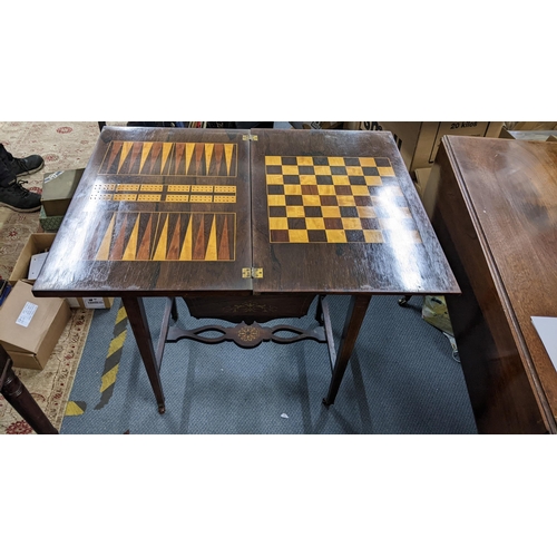 469 - An Edwardian rosewood combination games and work table having a fold over top and marquetry inlaid, ... 