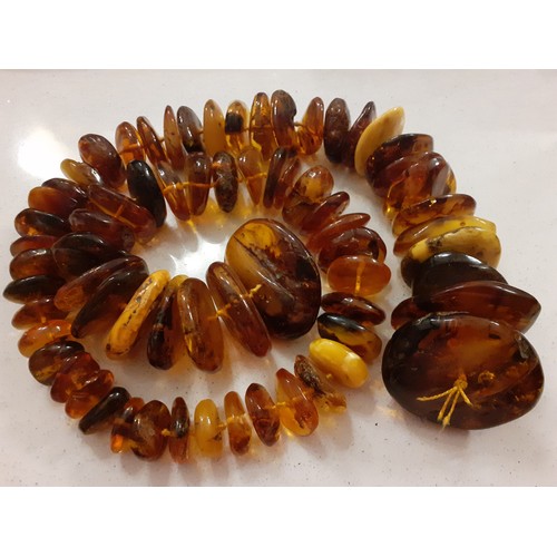 126 - A string of 68 vintage amber disc shaped beads of irregular form and varying colours to include butt... 