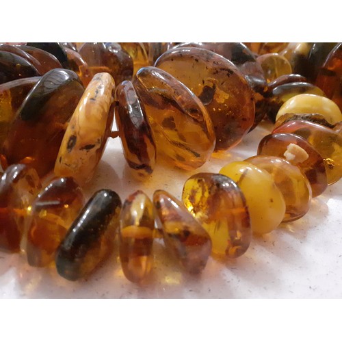 126 - A string of 68 vintage amber disc shaped beads of irregular form and varying colours to include butt... 