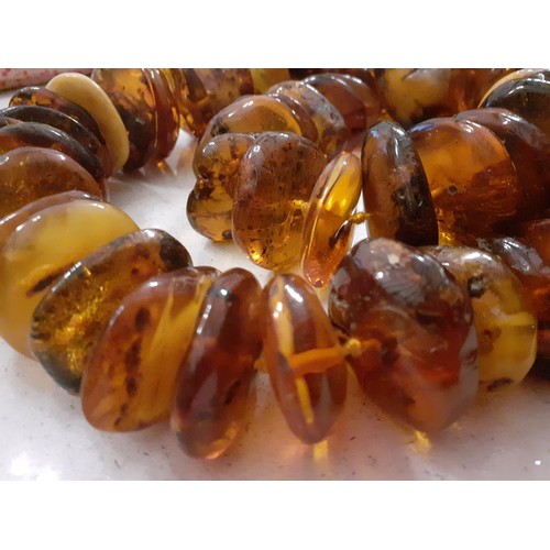 126 - A string of 68 vintage amber disc shaped beads of irregular form and varying colours to include butt... 