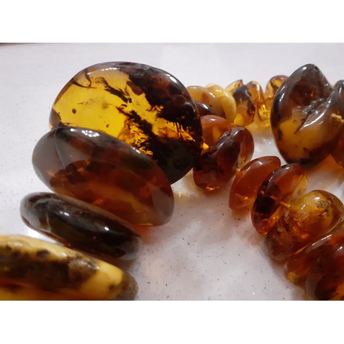 126 - A string of 68 vintage amber disc shaped beads of irregular form and varying colours to include butt... 