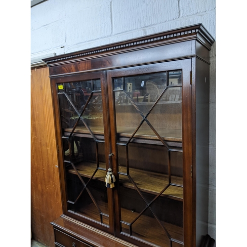 222 - Reproduction mahogany bookcase side cabinet, dental moulded cornice, above twin astragal glazed door... 