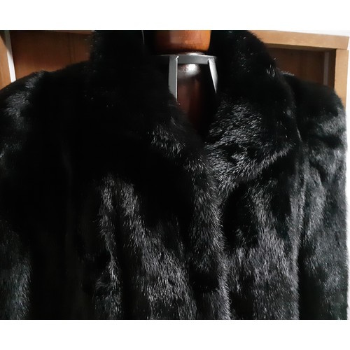 154 - A 1985 black mink knee length coat having bellow sleeves, shoulder pads and a black lining with mach... 