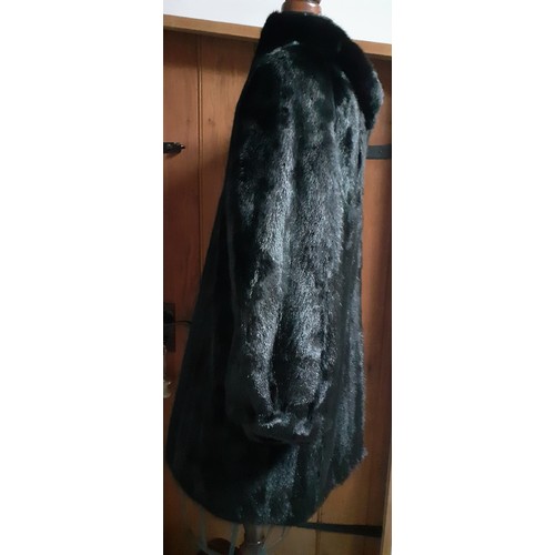 154 - A 1985 black mink knee length coat having bellow sleeves, shoulder pads and a black lining with mach... 