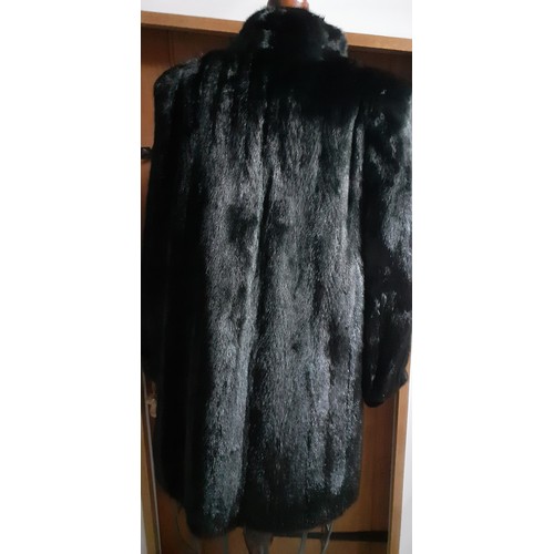 154 - A 1985 black mink knee length coat having bellow sleeves, shoulder pads and a black lining with mach... 