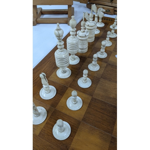 121 - A mixed lot to include a wooden chessboard, 50cm x 50cm, together with bone carved chess pieces, alo... 