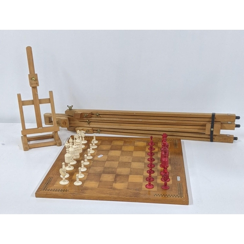 121 - A mixed lot to include a wooden chessboard, 50cm x 50cm, together with bone carved chess pieces, alo... 