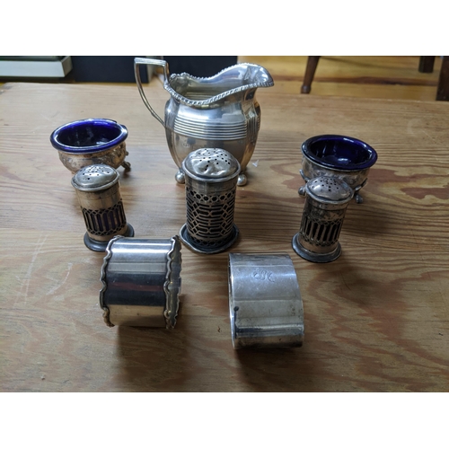 329 - A group of silver items to include a cream jug, two napkin rings, three piece cruet set and a pair o... 