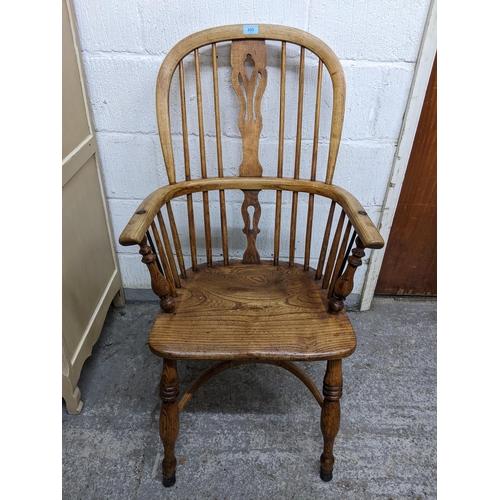 333 - A 19th century Windsor armchair with pierced centre splat, elm seat, ring turned legs united by a cr... 