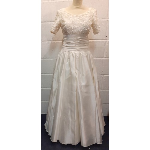 94 - A Donerica off white silk effect wedding dress having a zip fastening to the rear with large bow to ... 