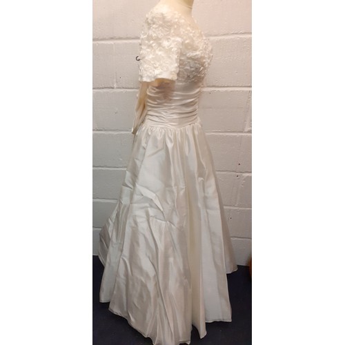 94 - A Donerica off white silk effect wedding dress having a zip fastening to the rear with large bow to ... 