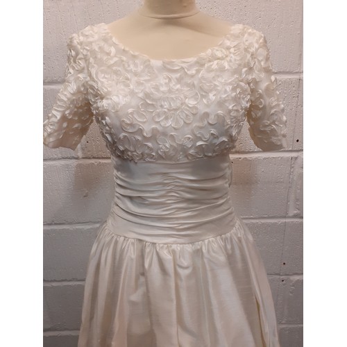 94 - A Donerica off white silk effect wedding dress having a zip fastening to the rear with large bow to ... 